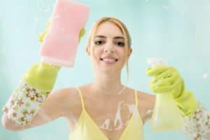 Efektywne sprzątanie z użyciem środk&oacute;w domowych, ścierka i spray, promienna kobieta w rękawicach.