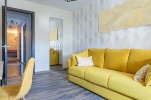 Naturalny ż&oacute;łty narożnik w nowoczesnym salonie z dekoracją na ścianie, stylowe wnętrze mieszkania.