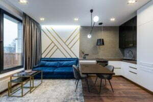 Nowoczesny salon z kuchnią, minimalistyczny wystr&oacute;j, wygodna sofa i nowoczesne oświetlenie.